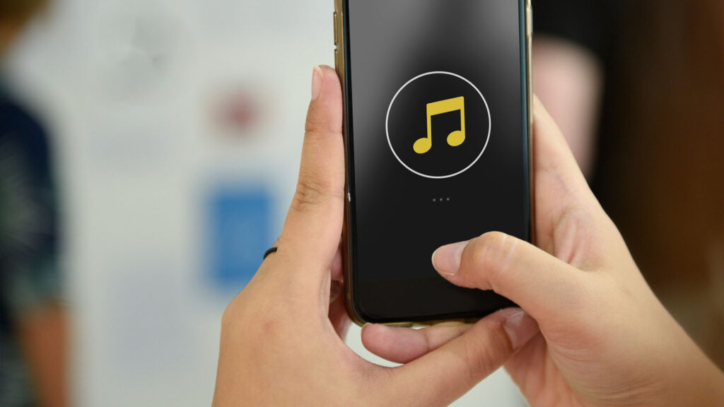 Eine Person hält ein Smartphone mit einem Musiksymbol auf dem Bildschirm und navigiert mühelos durch ihre Lieblingsmusik, ähnlich einer nahtlosen Website-Navigation.